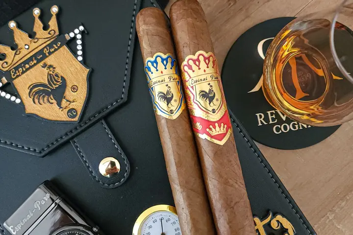 Dos cigarros Espinal Puro sobre un estuche de cuero junto a una copa de coñac