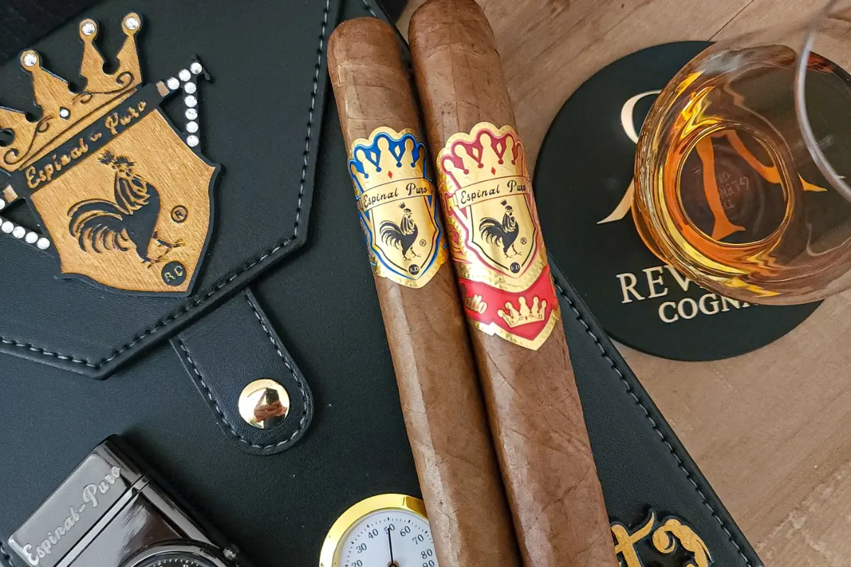 Dos cigarros Espinal Puro sobre un estuche de cuero junto a una copa de coñac